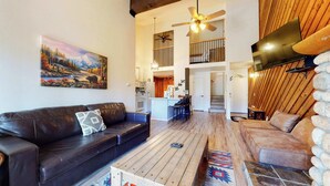 A spacious living area with a black leather sofa, a wooden coffee table, and a stone wall.