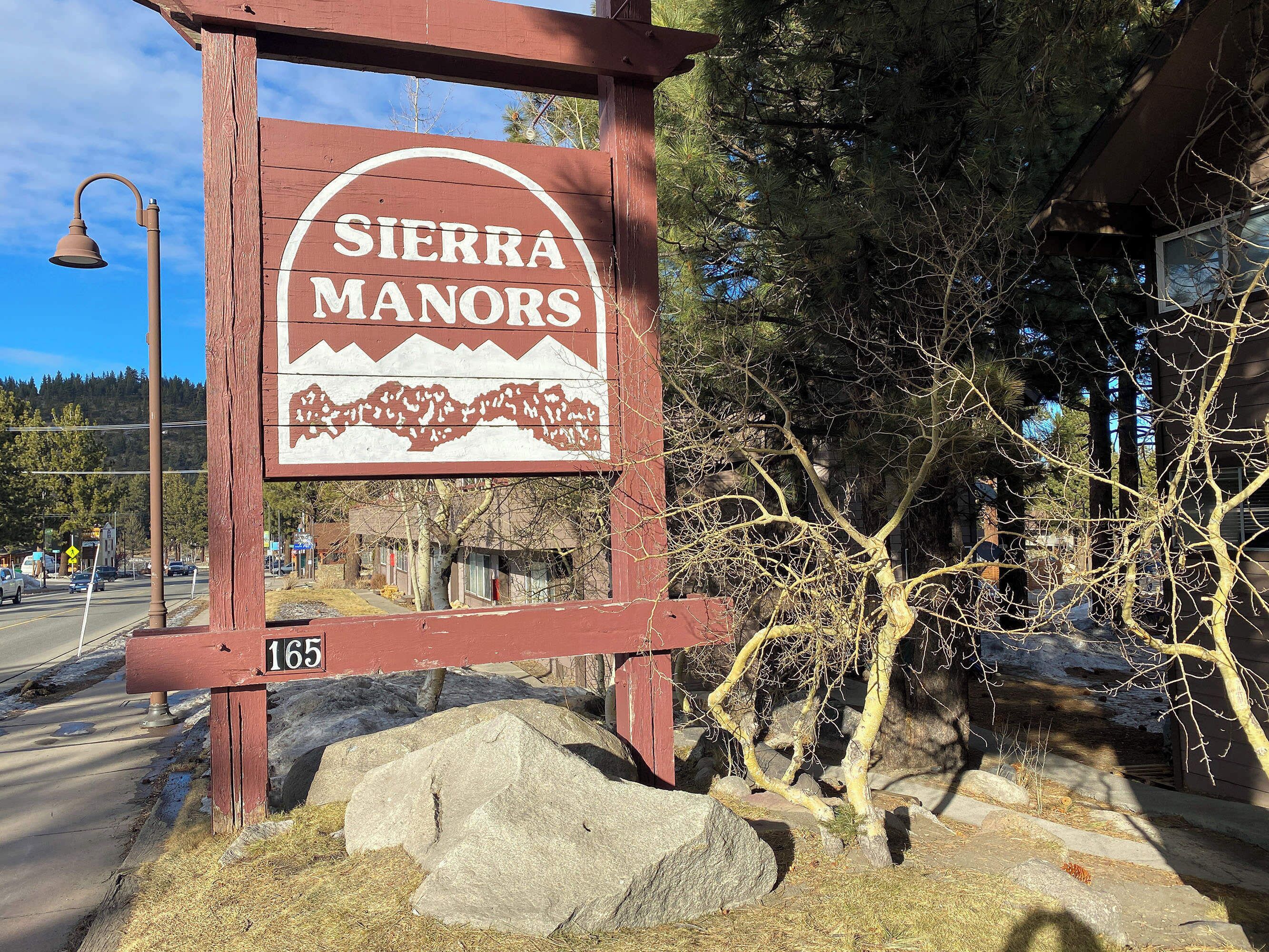En träskylt för Sierra Manors med en bergsbild och siffran 165.
