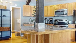 A modern kitchen with wooden cabinets, a central island, stainless steel appliances, and a built-in microwave.