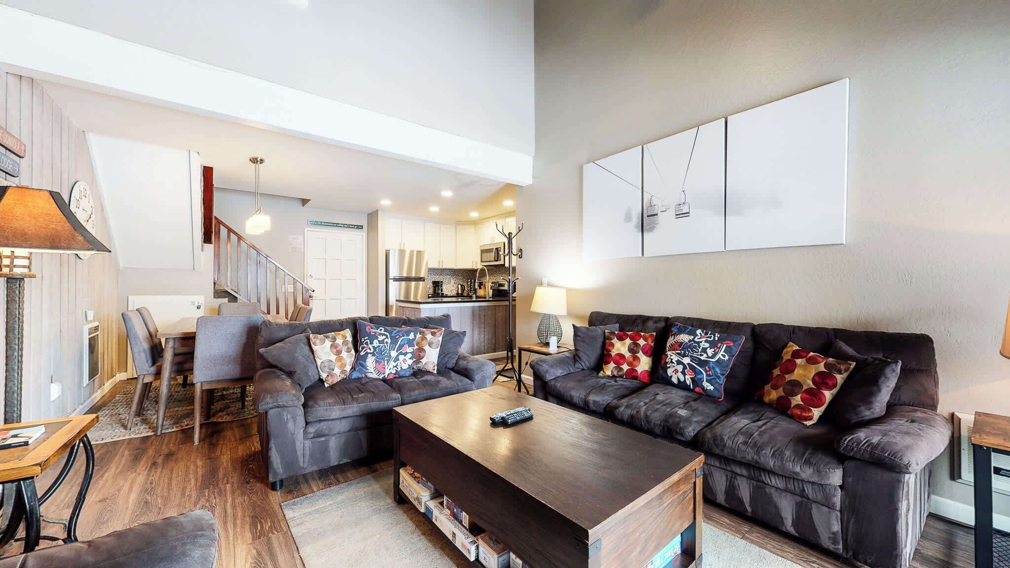 A modern living room with a dark leather sofa, a wooden coffee table, and a dining area with a table and chairs.