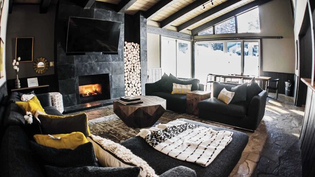 A cozy living room with a fireplace, comfortable seating, and large windows.