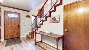 A wooden staircase with a handrail, a wooden door with a glass panel, and a sign on the wall. - Mammoth Pines #02 | Year-Round Activities! (Mammoth Lakes)
