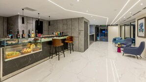 A modern hotel lobby with a marble floor, a reception area with a glass display case, and seating arrangements. - Coast Hotel (Boumerdès)