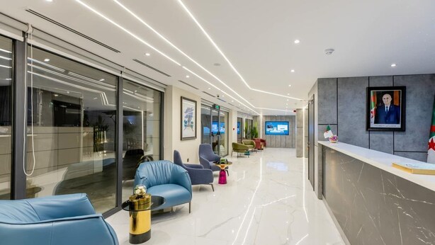 A modern lobby with glass walls, a reception desk, and seating areas. - Coast Hotel (Boumerdès)