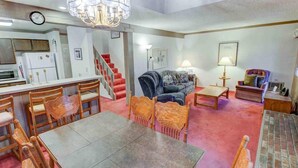 Un grand espace de vie comprenant une table à manger, des chaises, un canapé et un escalier menant à un autre niveau.