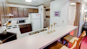 Une cuisine compacte avec un plan de travail blanc, une cuisinière, un four à micro-ondes et des placards en bois.