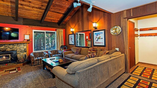 A cozy living room with a stone fireplace, a large sofa, and a television. - Horizons 4 | Year-Round Outdoor Activities! (Mammoth Lakes)