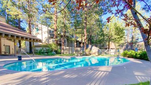 A swimming pool surrounded by trees and a building with a covered patio.