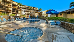 A hotel pool area with multiple lounge chairs and a hot tub.