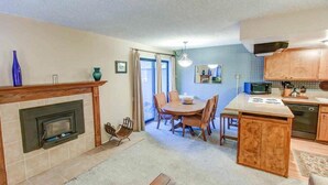 A compact kitchen with a central island, a dining area with a round table and chairs, and a fireplace. - Fireside | Pool Access, Hot Tub & More (Mammoth Lakes)