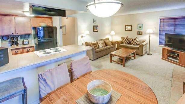 A compact living space with a kitchenette, a dining area, and a seating area with a sofa and TV. - Fireside | Pool Access, Hot Tub & More (Mammoth Lakes)