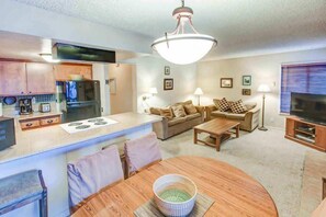 A compact living space with a kitchenette, a dining area, and a seating area with a sofa and TV. - Fireside | Pool Access, Hot Tub & More (Mammoth Lakes)