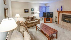 A cozy living room with a sofa, a coffee table, a TV, and a fireplace. - Fireside | Pool Access, Hot Tub & More (Mammoth Lakes)
