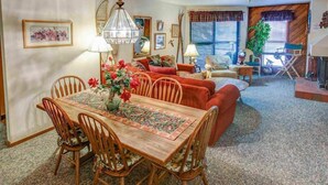 A cozy living room with a dining area, featuring a wooden table, chairs, and a sofa. - Shared Pool, Hot Tub & BBQ | Walk to Chairlift! (Mammoth Lakes)