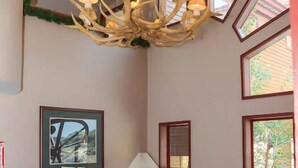 A living room with a chandelier, two sofas, a coffee table, and a framed picture on the wall. - Shared Pool, Hot Tub & BBQ | Walk to Chairlift! (Mammoth Lakes)