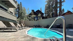 A swimming pool with a metal ladder, lounge chairs, and a stone-tiled deck. - Walk to Mammoth Ski Lifts | Ski Storage | Sleeps 6 (Mammoth Lakes)