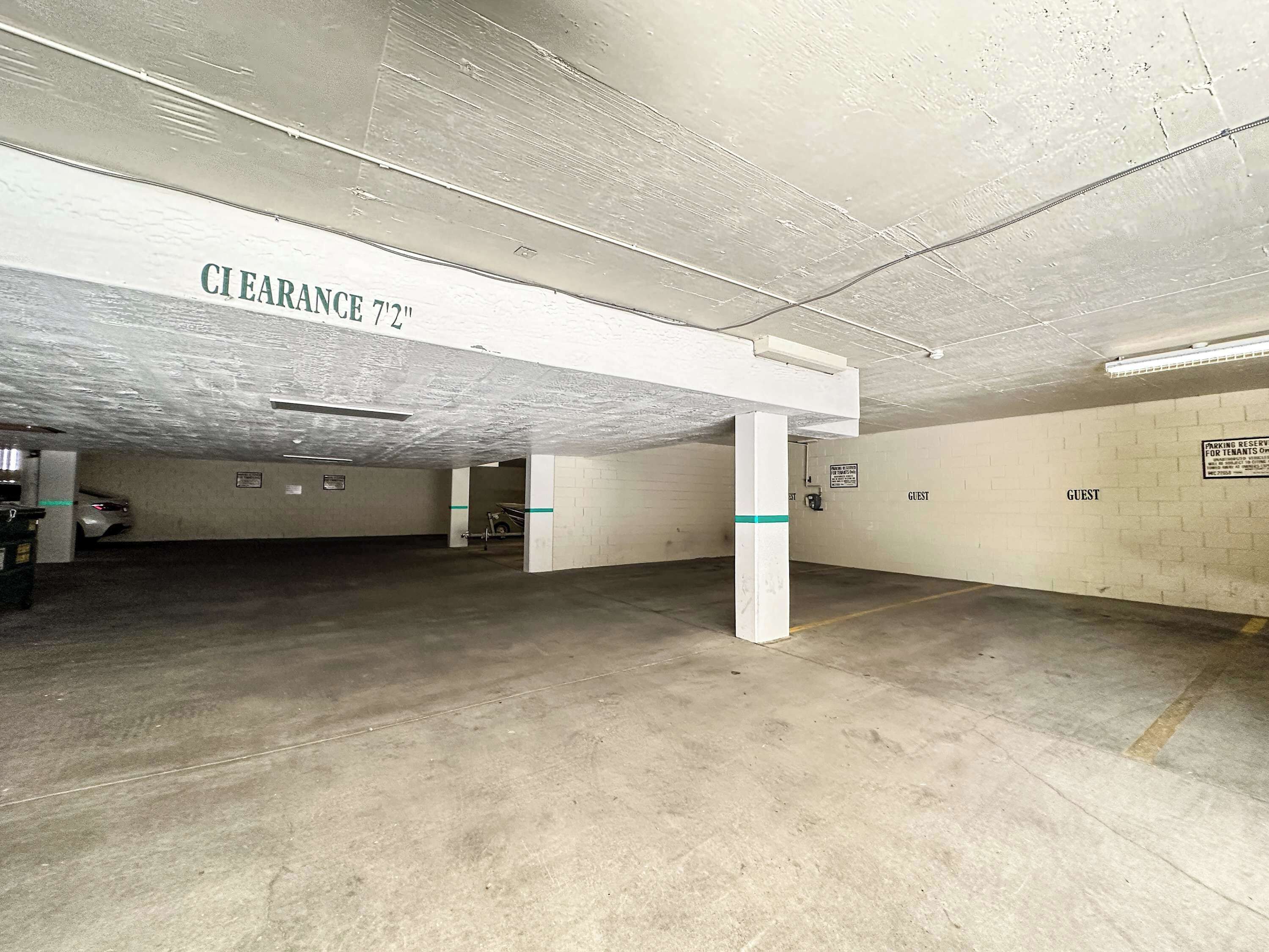 A parking garage with concrete floors and white walls, marked with 'CLEARANCE 7'2"'.