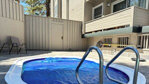 A swimming pool with metal ladders, surrounded by a tiled deck and a beige fence. - Walk to Mammoth Ski Lifts | Ski Storage | Sleeps 6 (Mammoth Lakes)