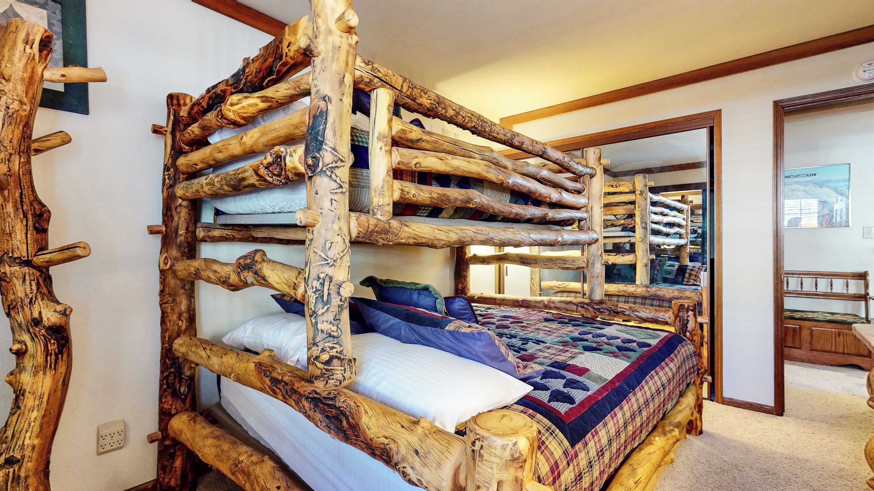 A rustic wooden bunk bed with a quilted bedspread and pillows.