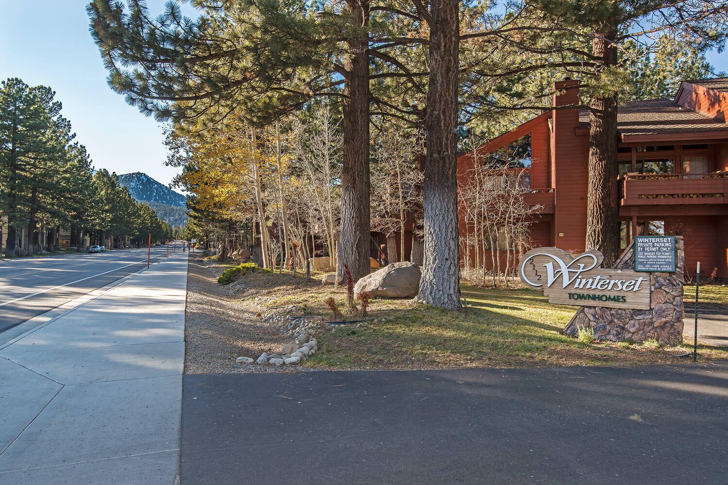A street view of Winterset Townhomes with a signboard, trees, and a building with a red facade.