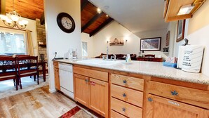 A kitchen with wooden cabinets, a dishwasher, a sink, and a clock on the wall.