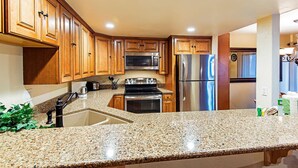 A kitchen with wooden cabinets, granite countertops, stainless steel appliances, and a built-in oven.