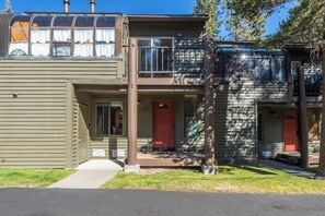 A two-story building with a garage, a front porch, and a red door.