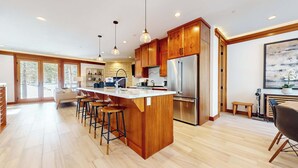 Una cocina moderna con armarios de madera, un refrigerador de acero inoxidable y una isla grande con taburetes.