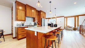 Una cocina moderna con armarios de madera, una isla grande con taburetes, un refrigerador y una estufa.