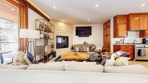 Una sala de estar moderna con un sofá de madera, una mesa de centro y un televisor montado en la pared.