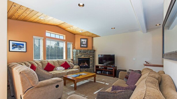 A cozy living room with a stone fireplace, a television, and comfortable seating.