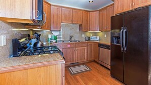 A kitchen with wooden cabinets, a black refrigerator, a stove, and a dishwasher.