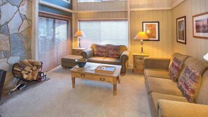 A cozy living room with a stone wall, a fireplace, a wooden coffee table, and two sofas.