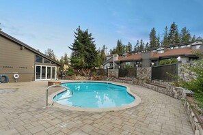 A swimming pool with a stone wall and a wooden deck.
