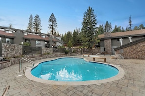 Una piscina con borde de piedra, rodeada por un patio empedrado.