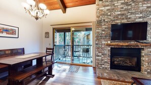 A cozy living room with a wooden bench, a fireplace, and a balcony with outdoor seating.