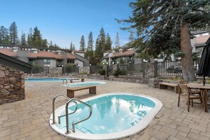 Un espace piscine comprenant deux piscines, des murs en pierre et une terrasse en bois.