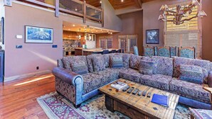 A spacious living room with a large sectional sofa, a wooden coffee table, and a high ceiling with exposed beams. - Group Townhouse | 4 Ensuite Beds, Den, Sleeps 12 (Mammoth Lakes)