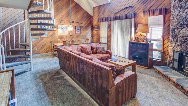 Un salon chaleureux avec un escalier en bois, un canapé, une table basse et une cheminée.