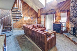 Un salon chaleureux avec un escalier en bois, un canapé, une table basse et une cheminée.