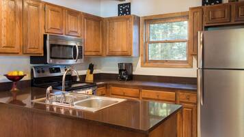 A kitchen with wooden cabinets, stainless steel appliances, a large island with a sink, and a window providing natural light.