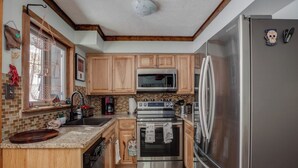 A modern kitchen with wooden cabinets, stainless steel appliances, and a brick backsplash.