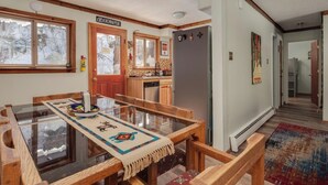 A dining area with a glass-top table, wooden chairs, and a patterned table runner.