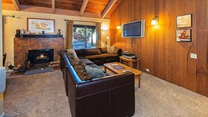 A cozy living room with a fireplace, a sofa, and a television mounted on the wall.
