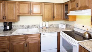 Eine Küche mit Holzausstattung, einem weißen Geschirrspüler, einem Herd und einer Kaffeemaschine.