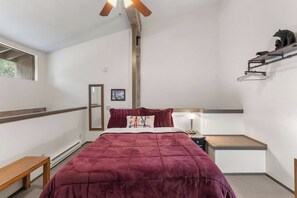 A bedroom with a bed, bedside table, lamp, and a shelf with decorative items. - Escape to The Summit | Cozy Mammoth Getaway (Mammoth Lakes)