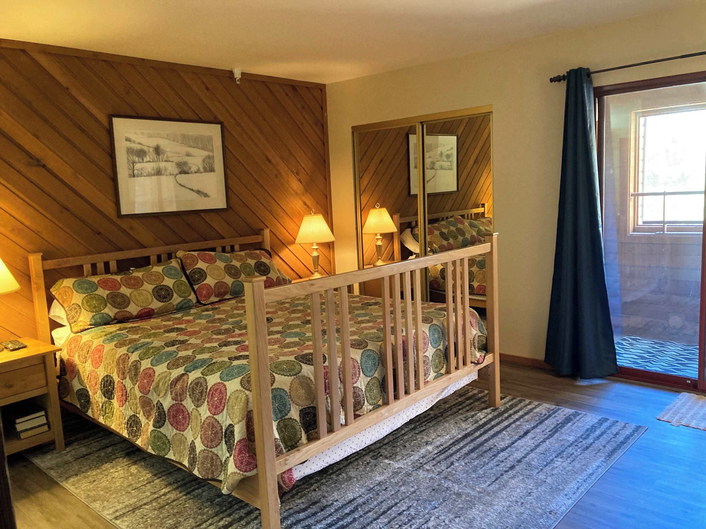 Une chambre à coucher avec un lit en bois, deux lampes de chevet, un tapis et une fenêtre avec des rideaux.