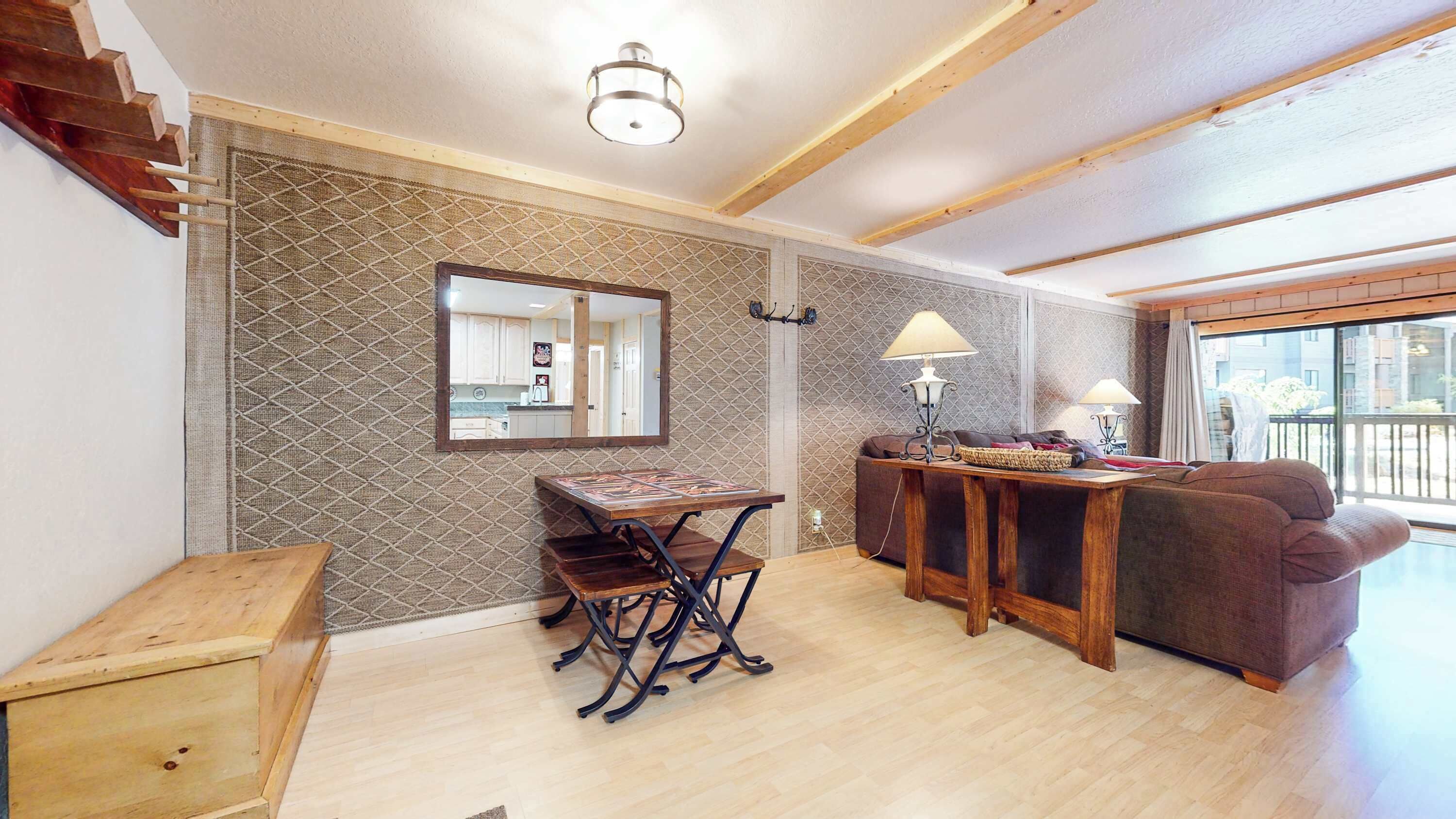 A spacious living area with a wooden dining table, a sofa, and a large mirror.