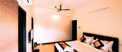A hotel room with a bed, a ceiling fan, and an air conditioning unit.