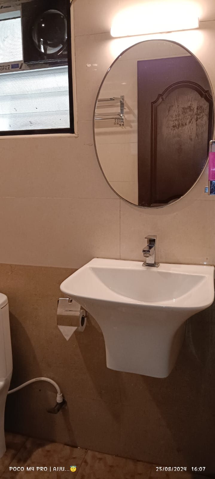 Un baño con un lavamanos blanco, un espejo y una ventana.